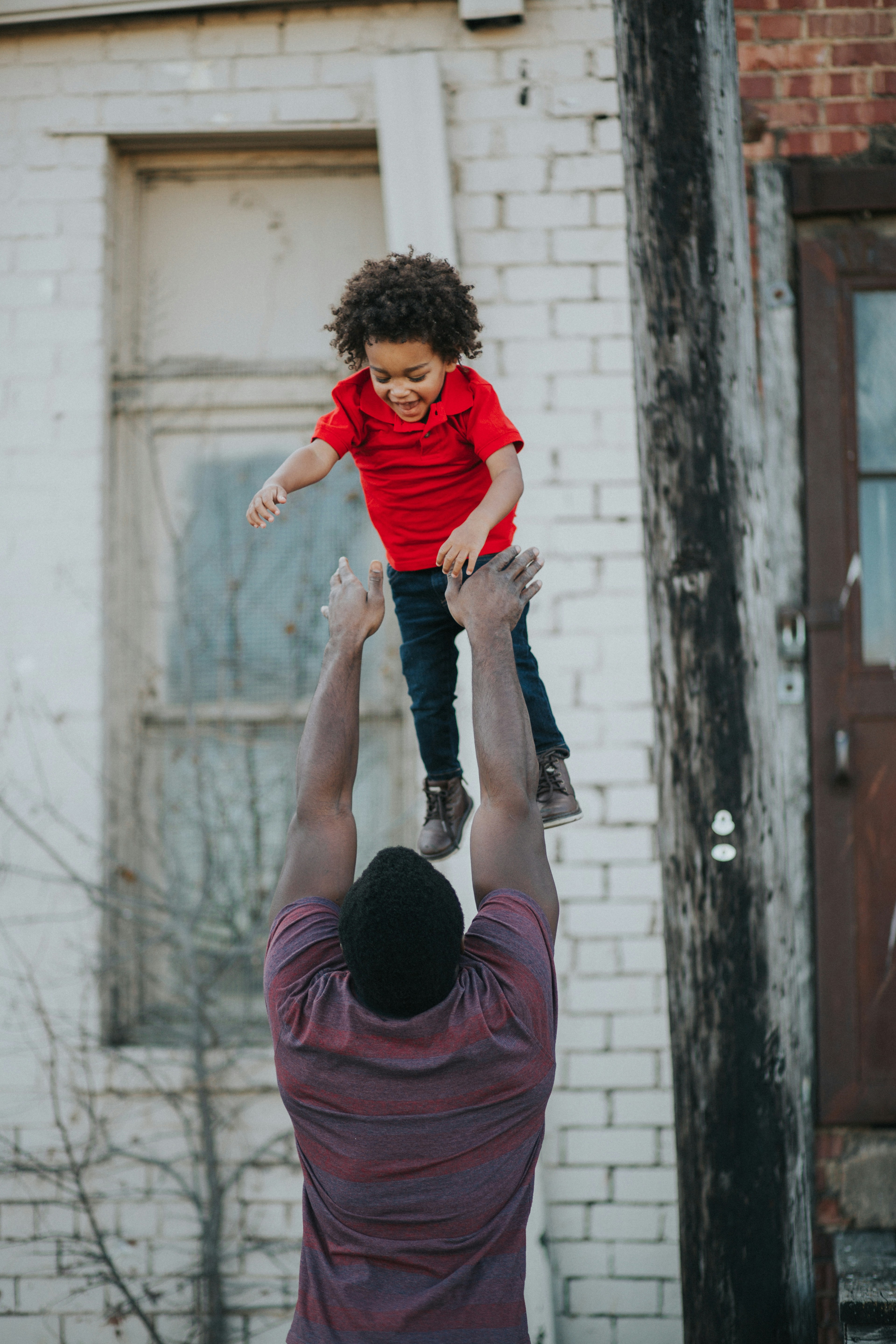 A father joyfully lifting his laughing child high into the air — the joy that financial stability makes possible