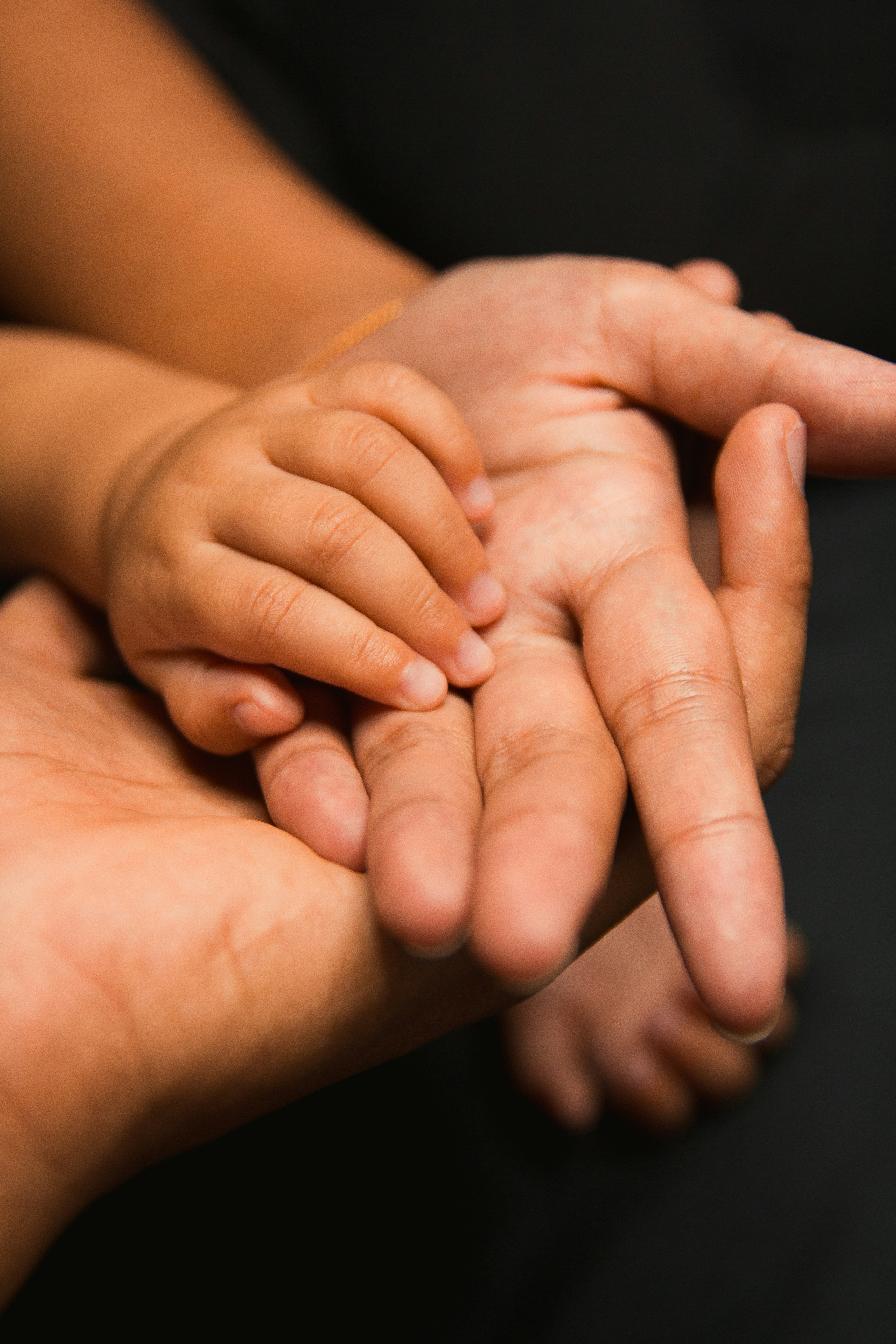 A baby's small hand resting gently in an adult's open palm — a sign of trust and care