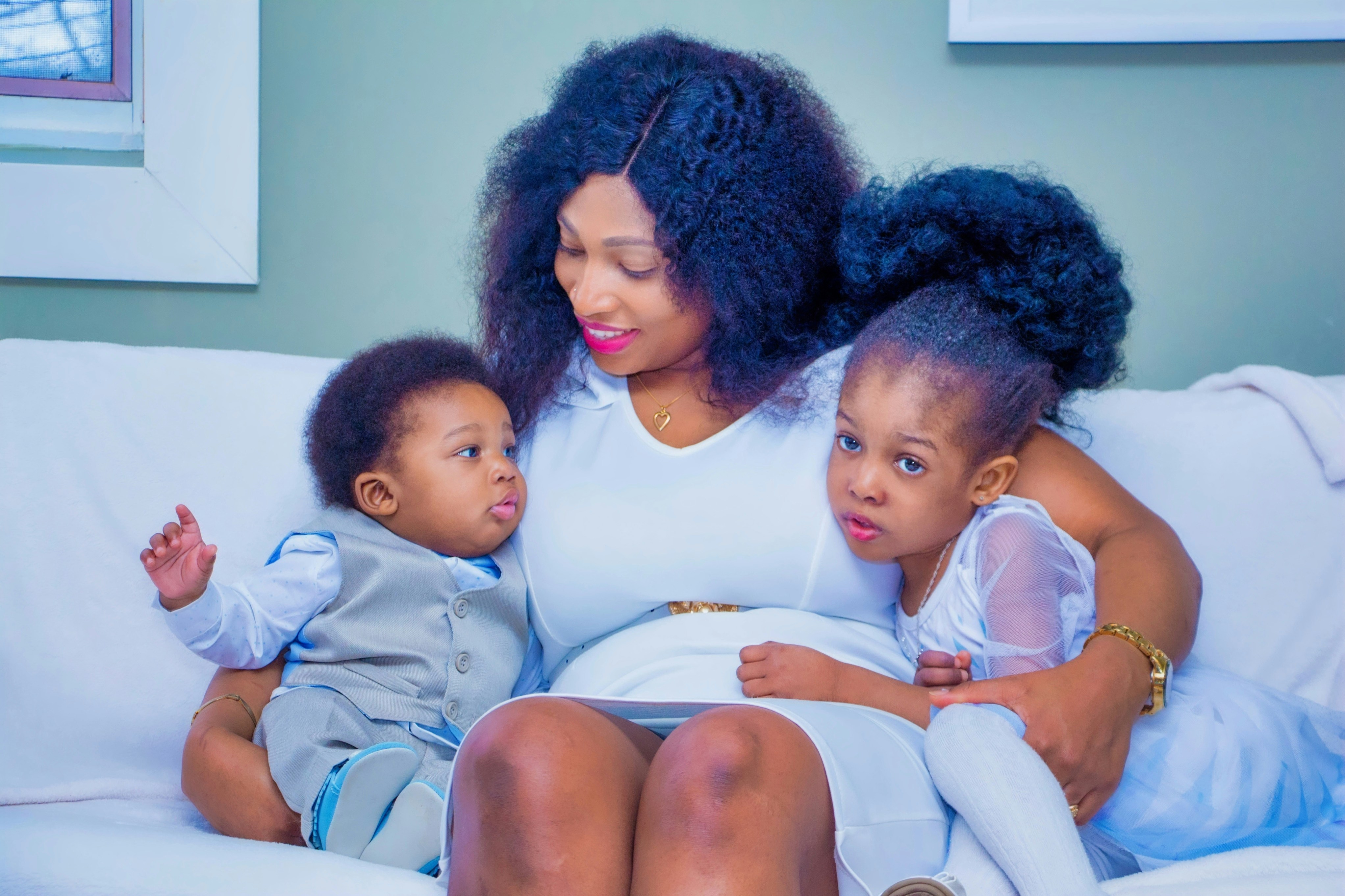 A mother seated on a sofa with her two young children, sharing a warm and joyful moment